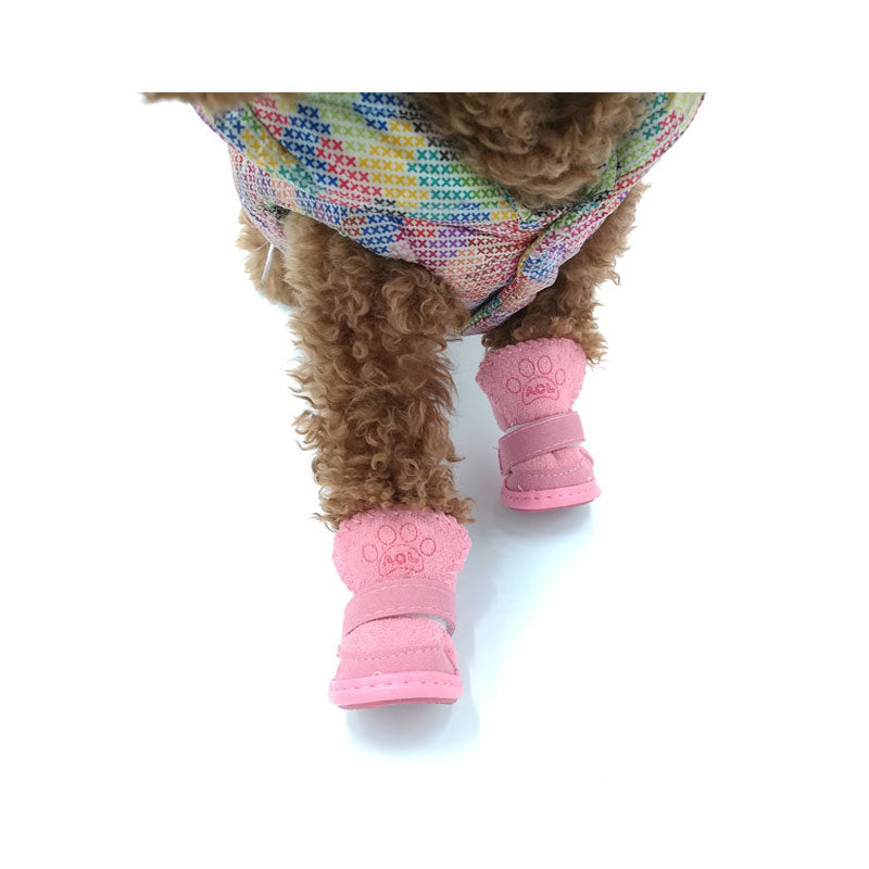 close up image of a small brown dog's front paws inside the pink snow boots, on a white background.