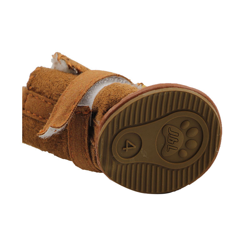 close up of the sole of a brown snow boot, showing the tread and strap. white background.