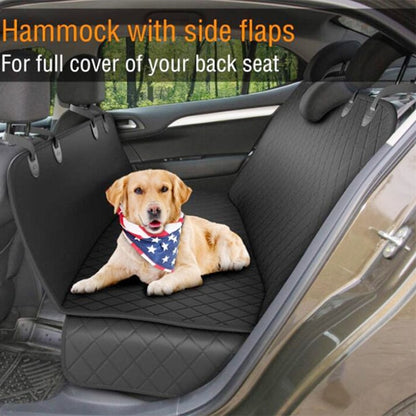 A Labrador dog sits in the back of a vehicle using the seat cover. The scene is outdoors and the dog wears an American flag bandana around it's neck. 