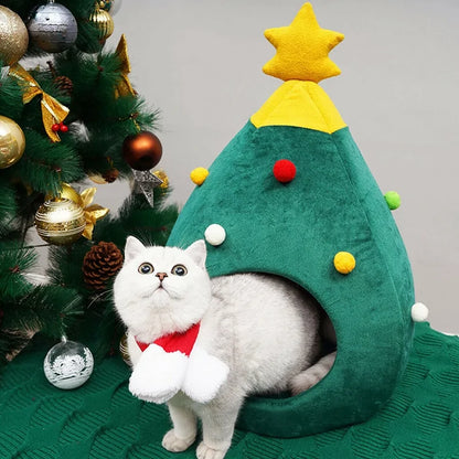 A white cat sits inside the Christmas Cat Bed in a home setting, next to a Christmas Tree. 