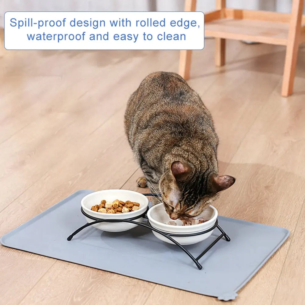 A tabby cat eats from a bowl placed on a grey Ultimate Silicone Pet Bowl Mat in a home setting