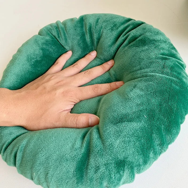 A human hand presses on the inner cushion of the Christmas Cat Bed to demonstrate softness and thickness of the cushion. White background 