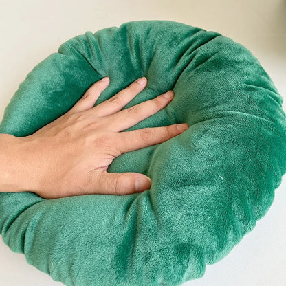 A human hand presses on the inner cushion of the Christmas Cat Bed to demonstrate softness and thickness of the cushion. White background 