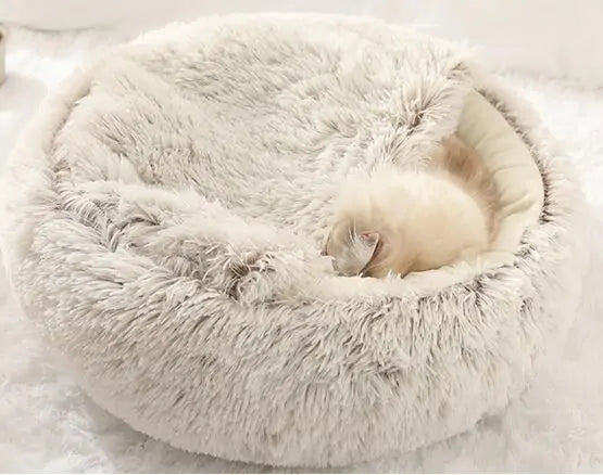 kitten sleeps in a grey snuggle bed in a home setting