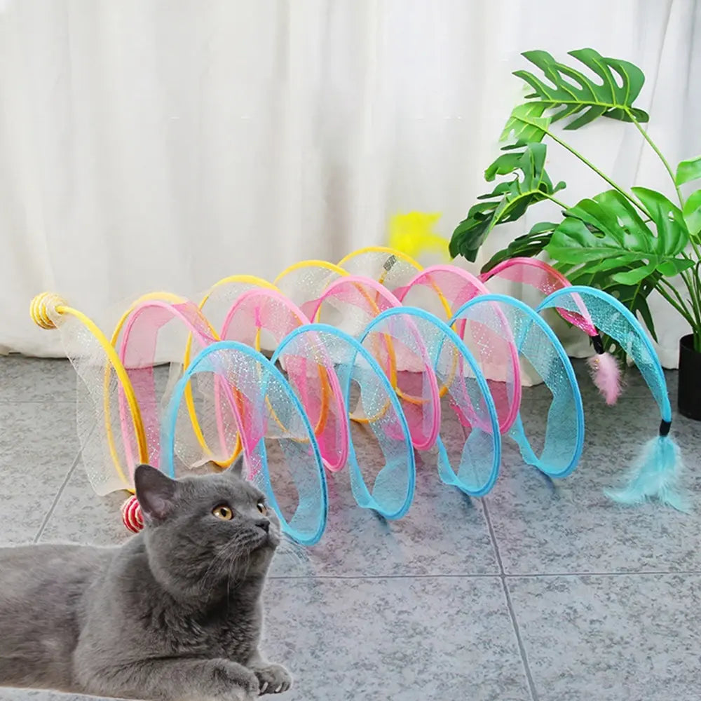 a shorthaired grey cat sits in a home setting, three Whisker Wonderland Cat tunnels are in the background 