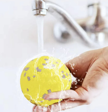 close up image of a yellow ball being washed under the tap. 