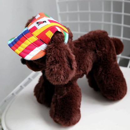 small brown plush toy dog, displaying a rainbow baseball cap, on a white and grey backdrop. 