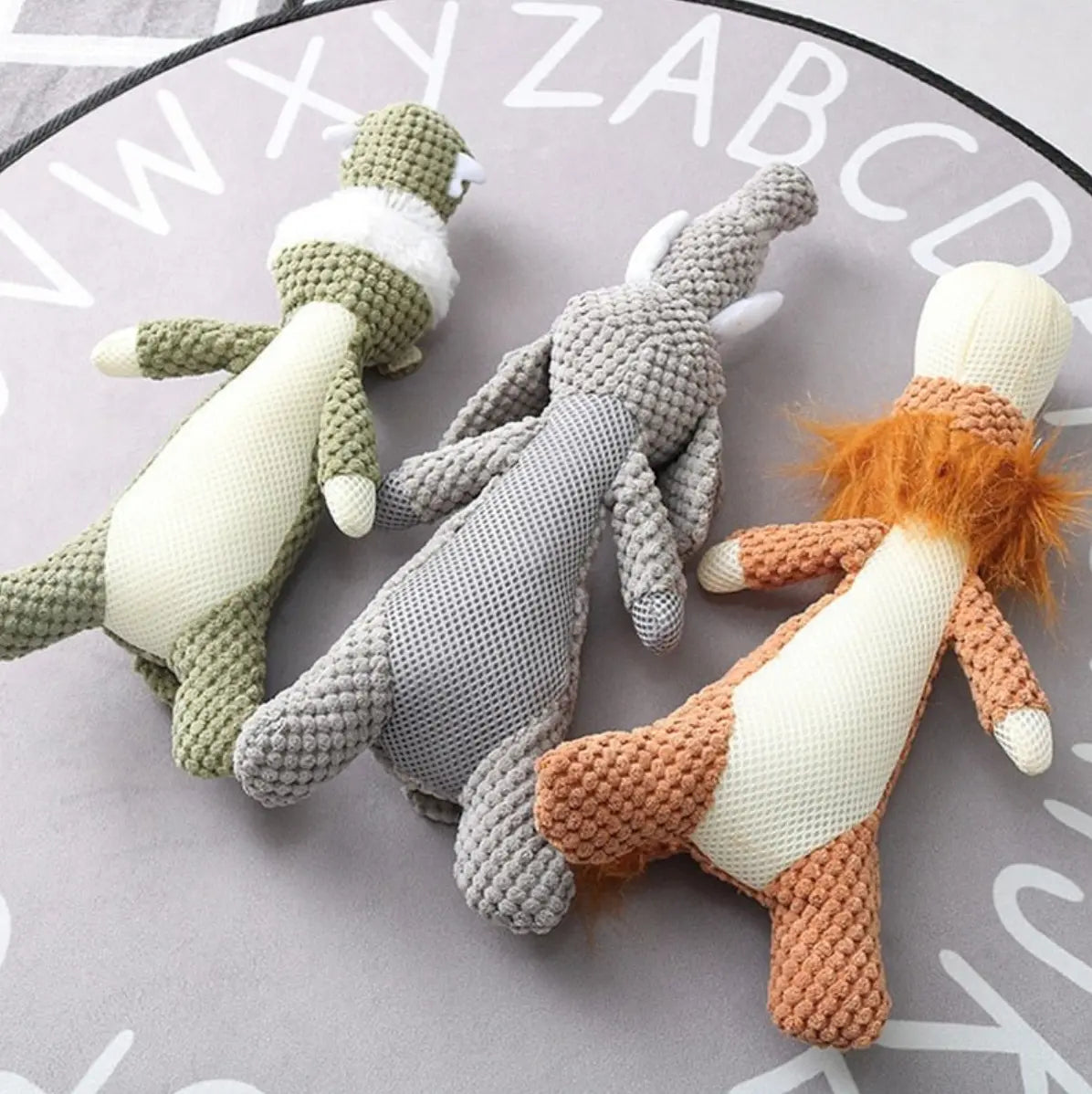 three designs of munchie chew toys lying upside down on a grey background. 