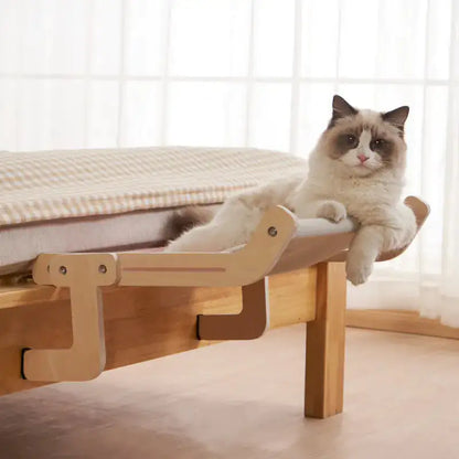 A white cat lies on a Feline Window Perch, which is attached to furniture, in a home setting