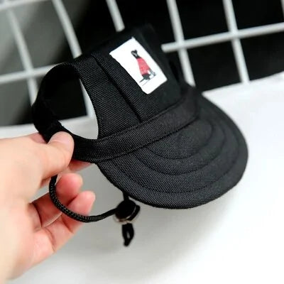 Black Pet  Baseball Cap in a person's hand against a white and black background. 