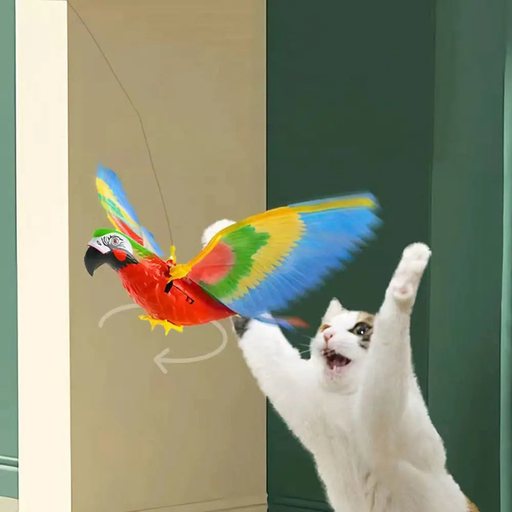 a rainbow colored flapping bird flies in an indoor setting, while a white at stretches up to catch the bird. 