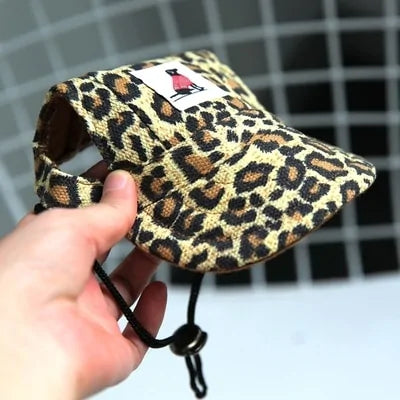 Leopard pattern Pet  Baseball Cap in a person's hand against a white and black background. 