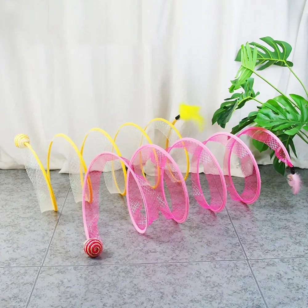 pink and yellow Whisker Wonderland Cat Tunnels on a grey floor in a home setting. 
