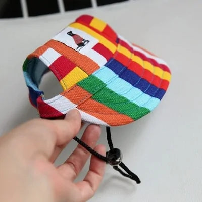 Rainbow Pet  Baseball Cap in a person's hand against a white and black background. 