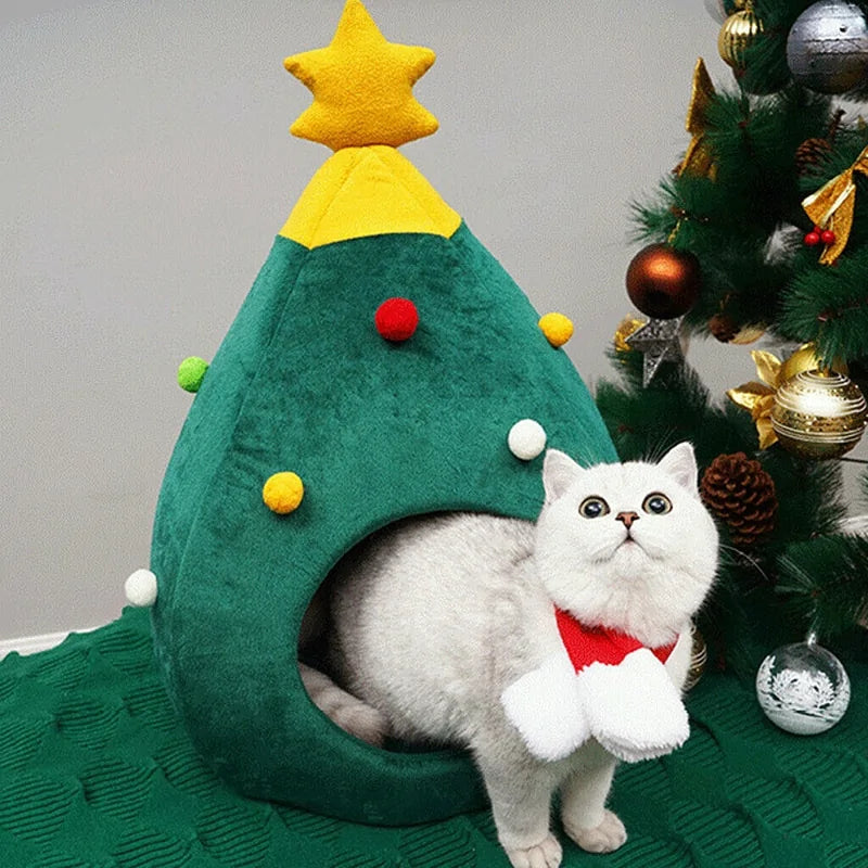 A white cat sits inside the Christmas Cat Bed in a home setting, next to a Christmas Tree. 