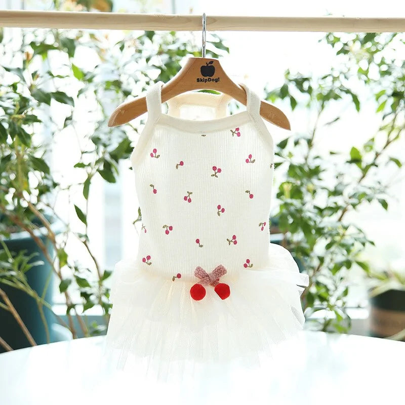 Cheery Delight Dog dress on a hanger, green foliage sets the background 