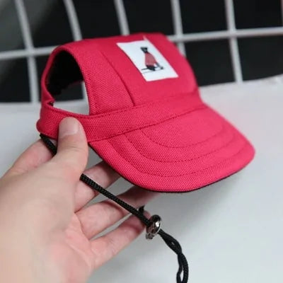 Red Pet  Baseball Cap in a person's hand against a white and black background. 