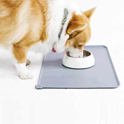 A corgi dog eats from a bowl on a grey Ultimate Silicone Pet Bowl Mat, white background 