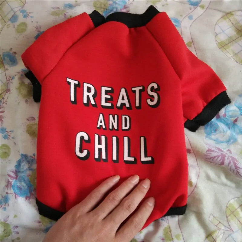 Red 'Treats and Chill' Pet Jacket on a floral surface. 