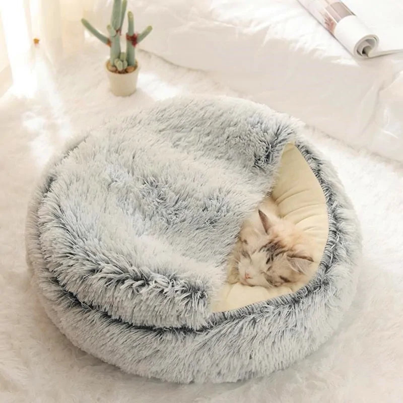 a kitten sleeps in a grey snuggle bed in a home setting