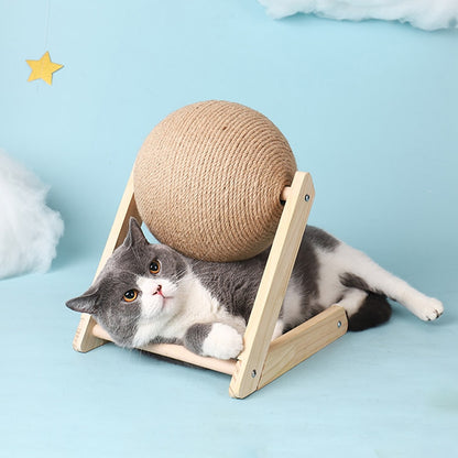 grey and white cate lies under the cat scratch ball, blue background. 