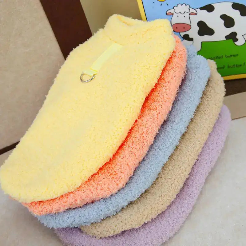 a stack of the five different colored sweaters in a home setting - yellow, apricot, blue, beige and purple. 