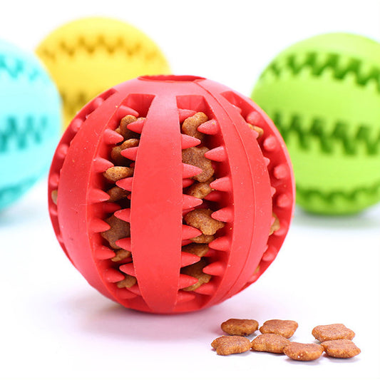 white background, red chewable treat dispenser ball filled with dry dog food in the forefront, a yellow, green and blue ball are in the background.